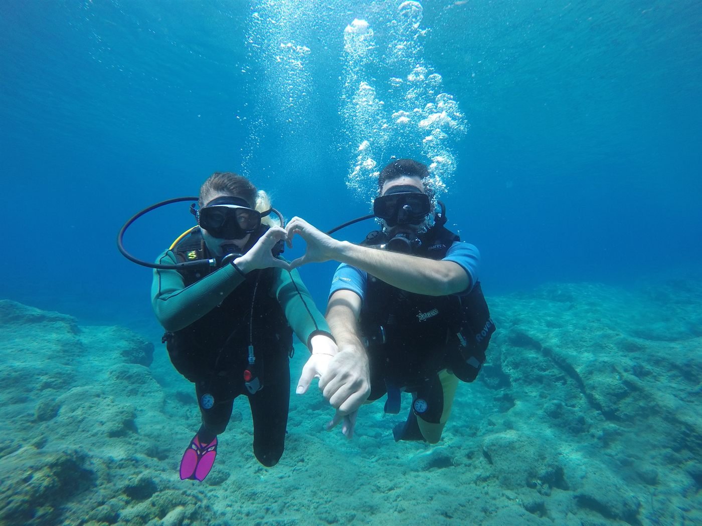 Zwei Taucher formen unter Wasser mit den Händen ein Herz